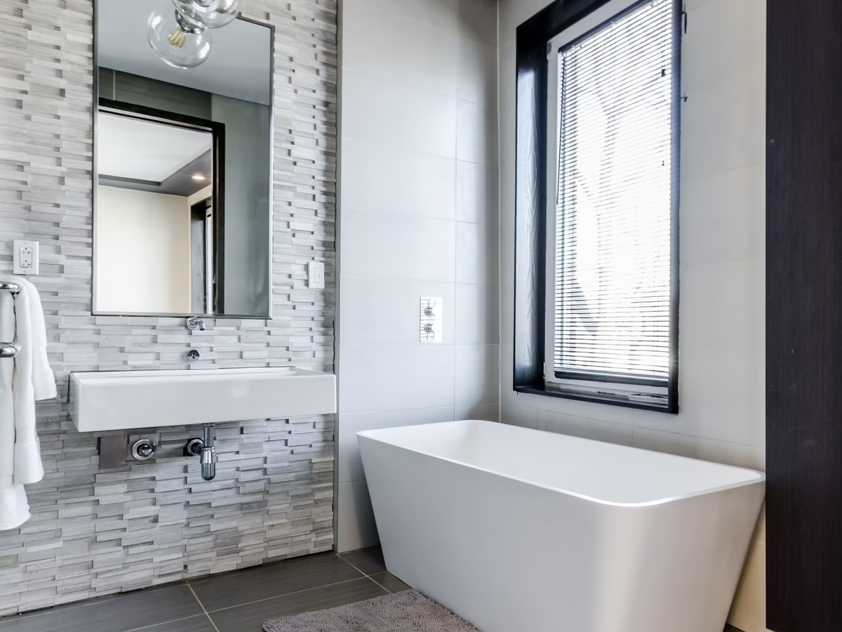 Bathroom with stacked stone feature wall, large-format floor tile and soaking tub